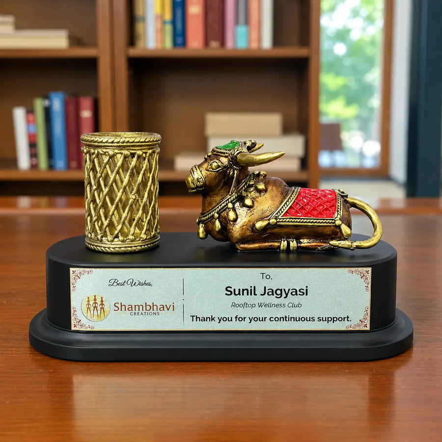 Bastar Dhokra brass nandi with red saddle and brass pen holder on a black wooden base with personalized name plate, styled on an office desk