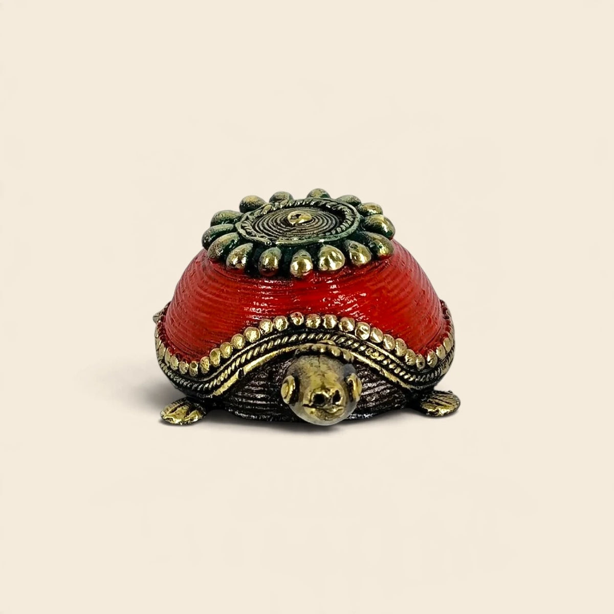 Front view of Bastar Dhokra brass turtle with head peeking out under the red ridged shell and beaded brass rim