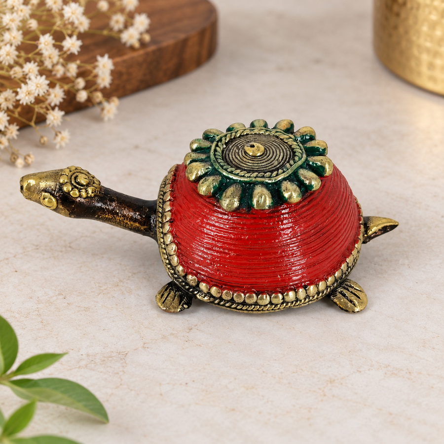 Handcrafted Bastar Dhokra brass turtle trinket box with red coiled shell and green floral lid, placed on marble