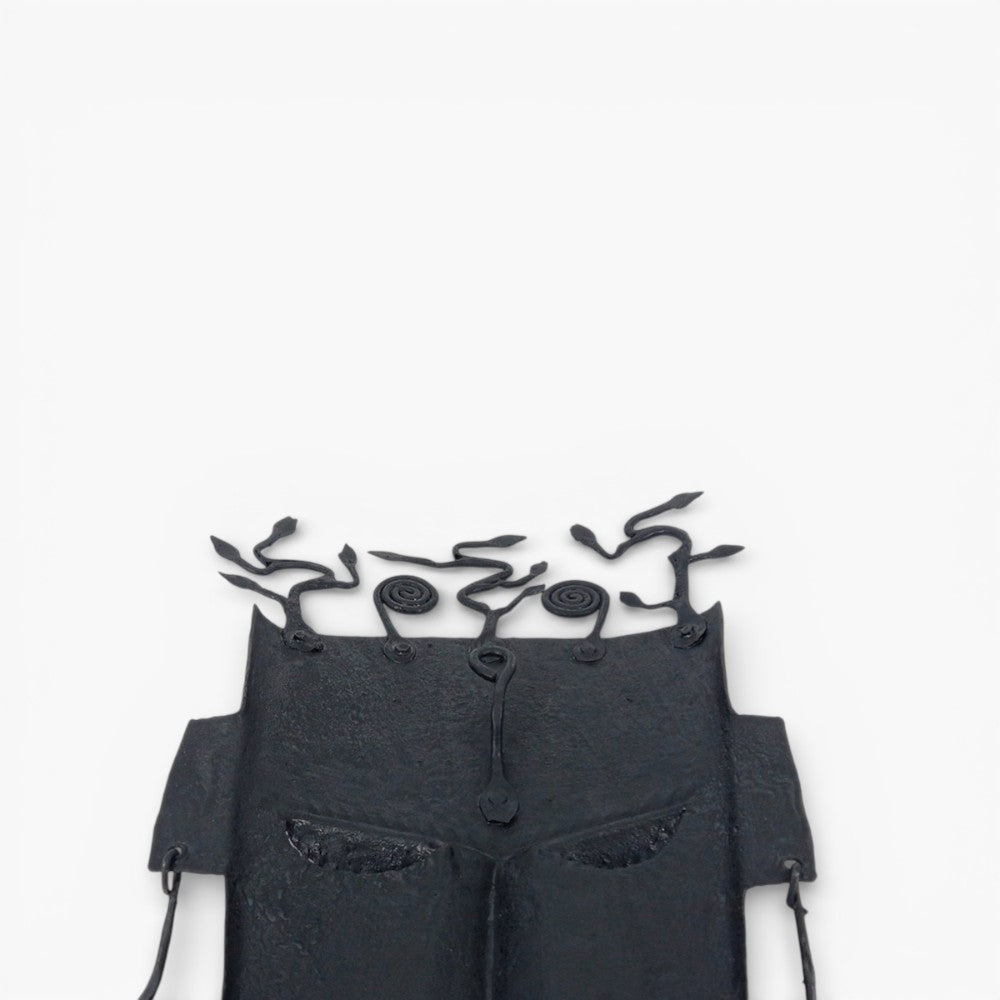 Detail view of abstract tree motif crafted in Bastar iron art on tribal wall mask with matte black hand-forged finish