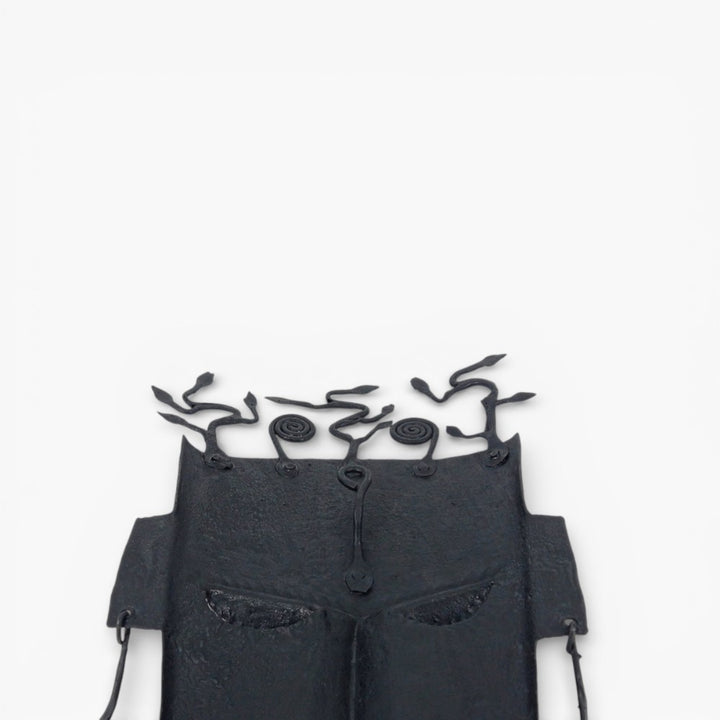 Detail view of abstract tree motif crafted in Bastar iron art on tribal wall mask with matte black hand-forged finish