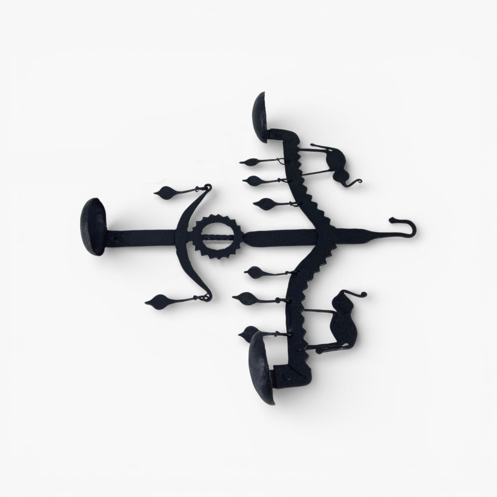 Angled flat lay view of Bastar iron art elephant wall hanging highlighting handmade iron texture and diya bowls