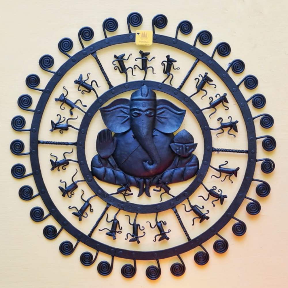 Handmade Bastar iron craft round Ganesha wall hanging displayed on a light wall, showcasing traditional wrought iron detailing and circular folk design