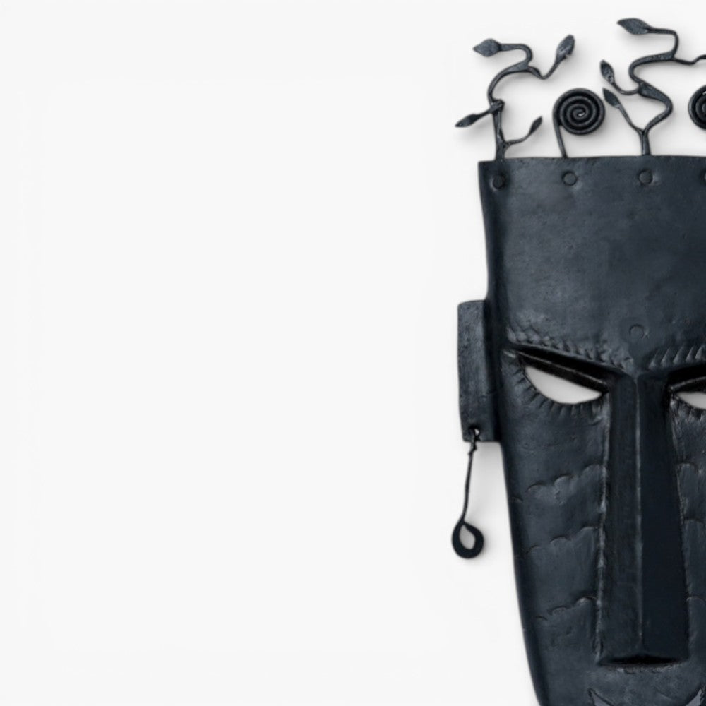 Close-up of handmade Bastar iron tribal wall mask showing hand-etched facial features and textured black iron surface