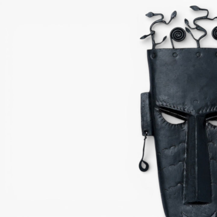 Close-up of handmade Bastar iron tribal wall mask showing hand-etched facial features and textured black iron surface
