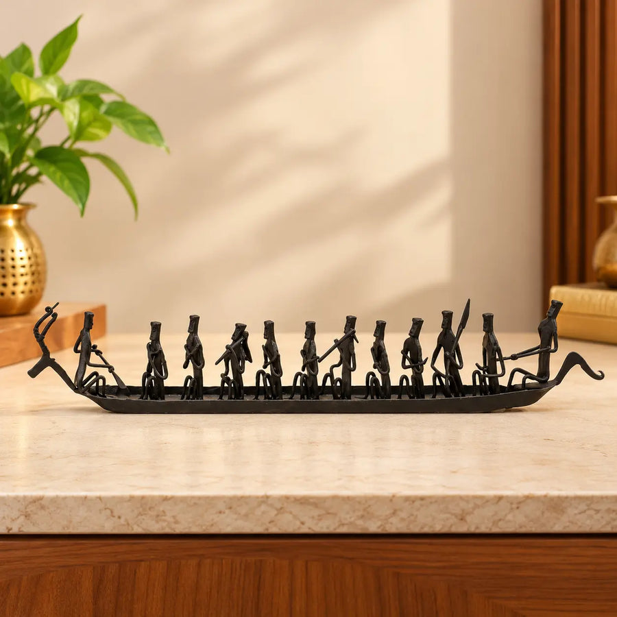Handcrafted wrought iron deer boat showpiece with rowers, Bastar Loha Shilp art, placed on a marble console beside a brass vase