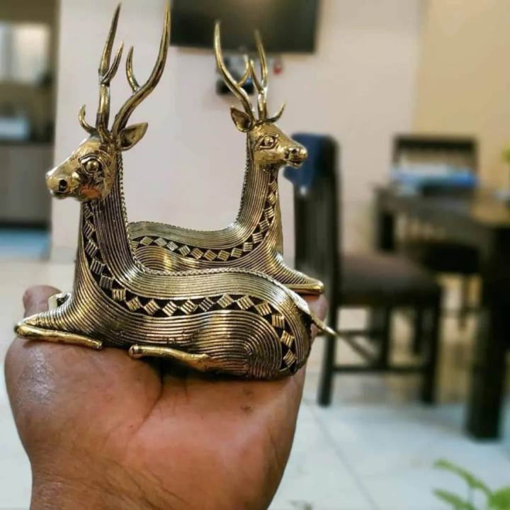 Artistic studio shot of brass bell metal sitting deer duo with graceful antlers and flowing body lines
