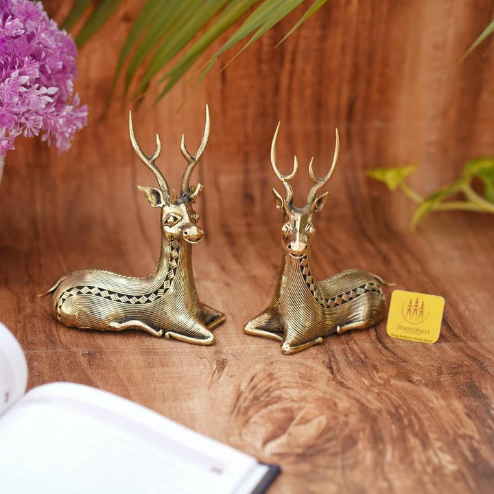 Handcrafted brass bell metal sitting deer duo placed on a wooden surface as elegant home decor showpieces