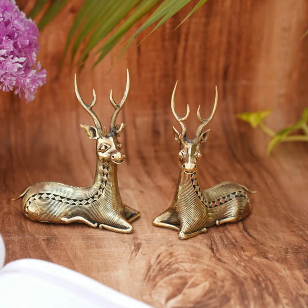 Handcrafted brass bell metal sitting deer duo placed on a wooden surface as elegant home decor showpieces