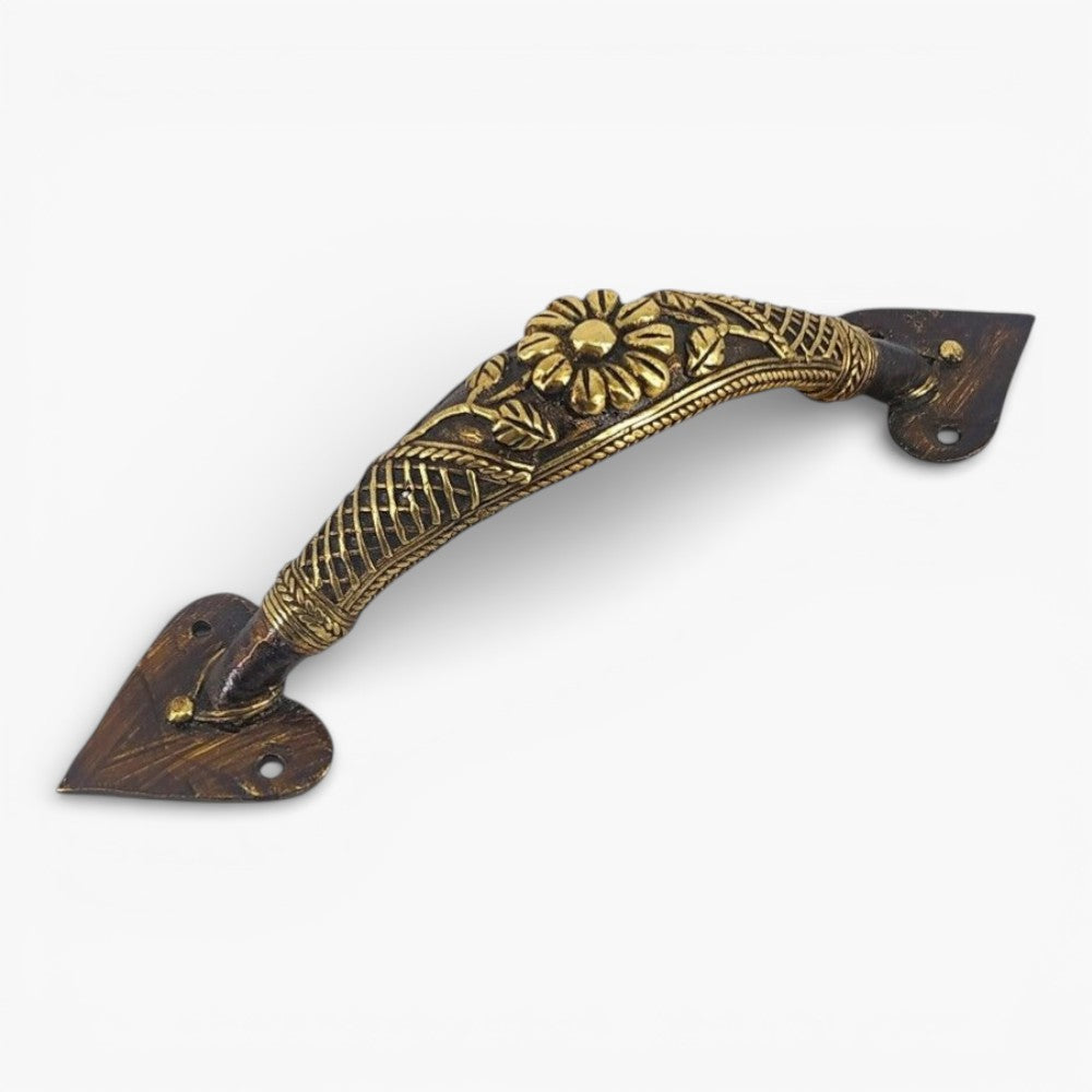 Low side angle view of handcrafted brass door handle highlighting curved form and textured lattice detailing