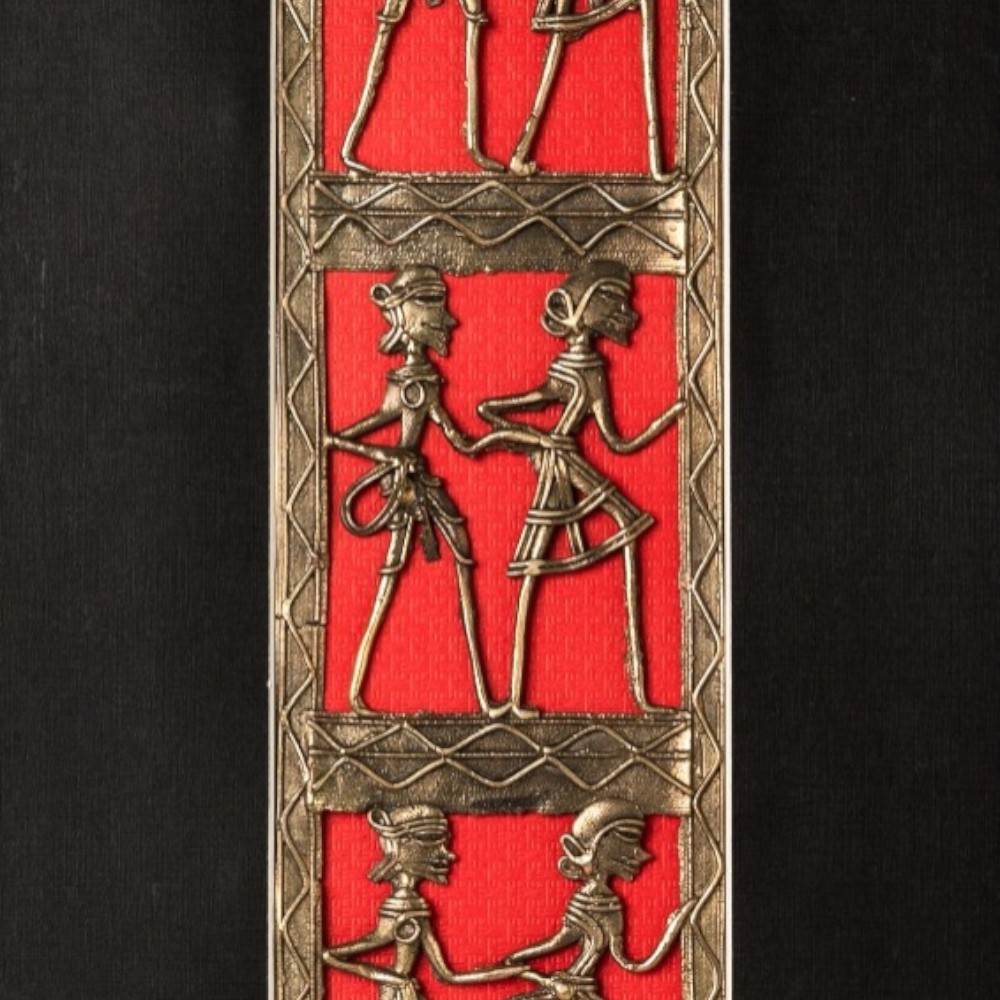 Close view of Bastar Dokra art brass dancing figurines mounted on red fabric panel in black wooden wall frame