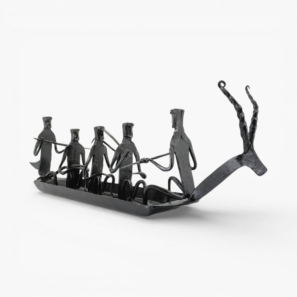 Front angled view of handcrafted Bastar iron art Kerala boat tabletop showpiece featuring tribal figures and rustic black finish
