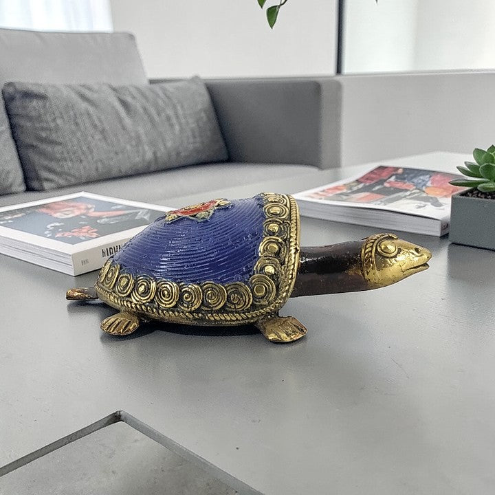 Handmade tribal art bell metal coin tortoise in blue color displayed in a lifestyle setting highlighting traditional Dhokra craftsmanship