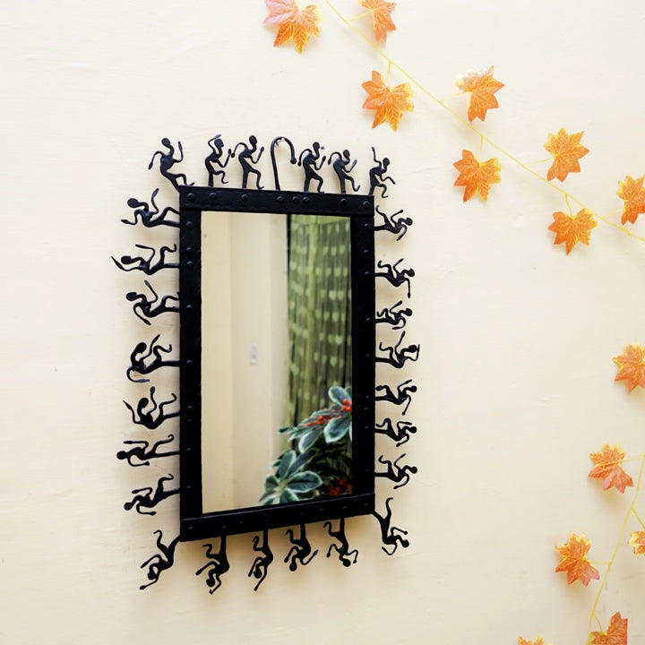 Handmade Bastar art wrought iron rectangular wall mirror displayed on a wall, featuring folk figure detailing around the frame and a matte black artisanal finish