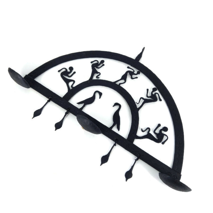 Handcrafted Bastar iron art half circle wall hanging photographed at an angle, highlighting black wrought iron texture, folk art silhouettes, and diya holders