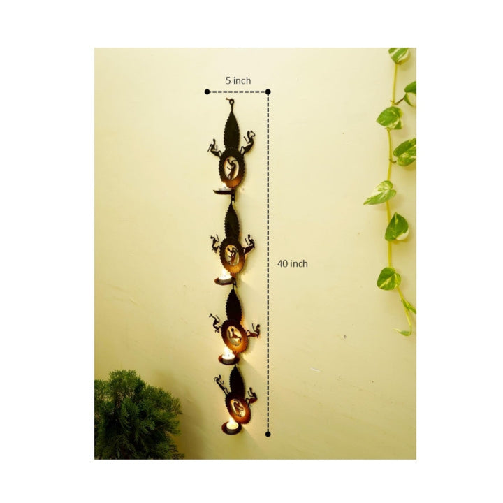 Handmade Bastar iron craft leaf design tea light wall hanging shown on a wall with height measurement, emphasizing vertical form, four diya holders, and traditional Loha Shilp detailing