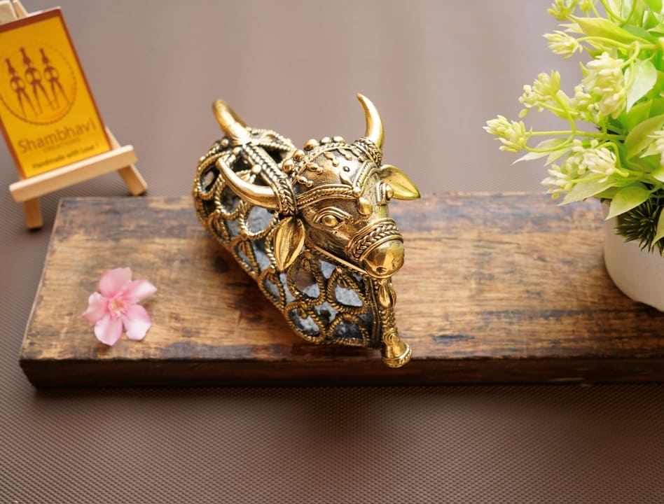 Handcrafted brass Nandi sitting statue placed as a spiritual home décor accent with lamp light enhancing jali work