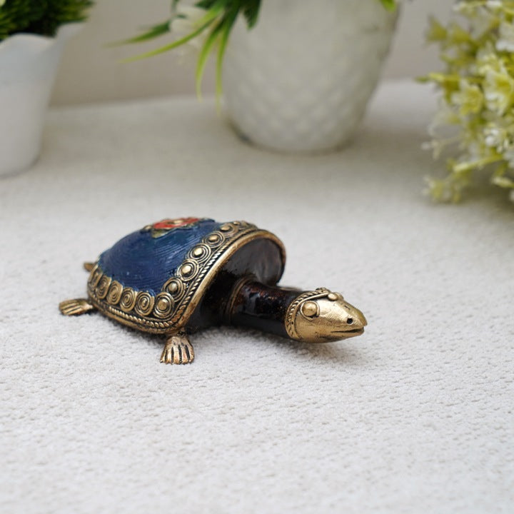 Handmade tribal art bell metal coin tortoise in blue color displayed in a lifestyle setting highlighting traditional Dhokra craftsmanship