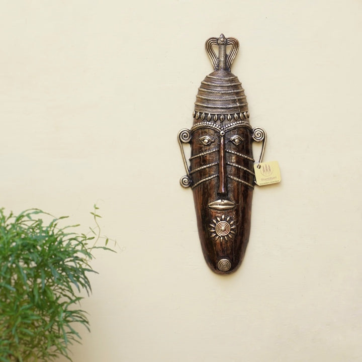 Handcrafted Bastar art long face tribal brass mask in bronze finish displayed on wall in a lifestyle setting for home and office decor