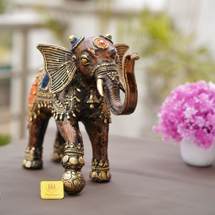 Handcrafted bronze dhokra soccer playing elephant statue shown in outdoor lifestyle setting with decorative detailing